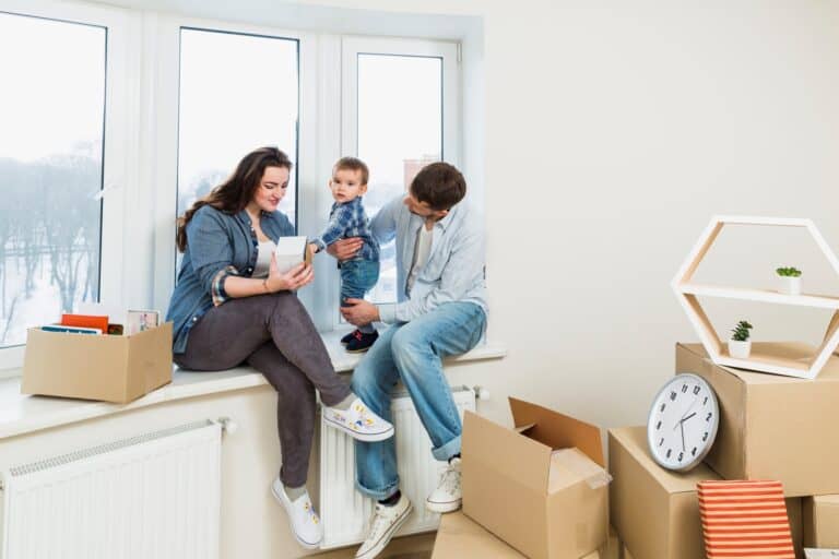 A young family by the window after the house relocation in the concept of 'How to Settle into a New Home After Moving'.