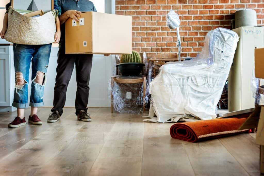 Cropped image of a couple arrive in their new flat carrying boxes in the concept of 'how to pack and unpack for a home removal efficiently'.